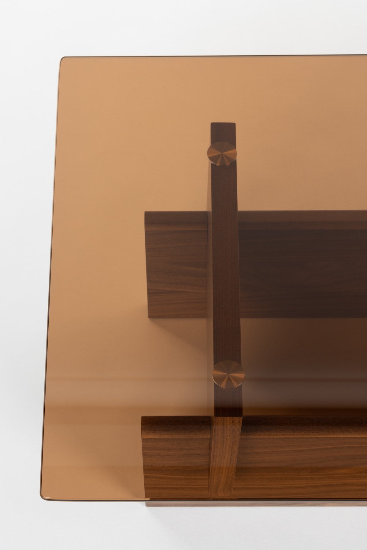 Couchtisch Lucifer Walnut von Dutchbone mit braunem Holzgestell aus zwei quer angeordneten Platten und rechteckiger Glasplatte.