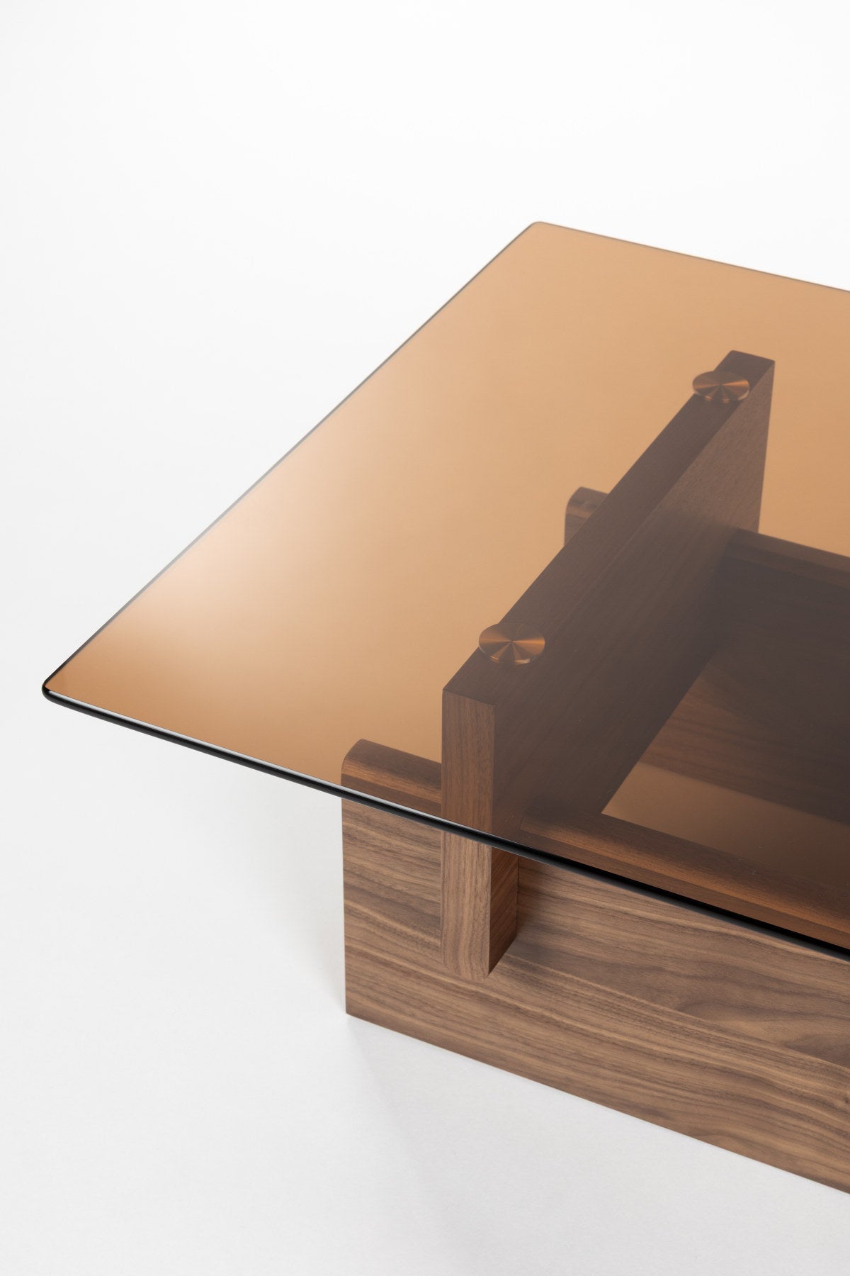 Couchtisch Lucifer Walnut von Dutchbone mit braunem Holzgestell aus zwei quer angeordneten Platten und rechteckiger Glasplatte.