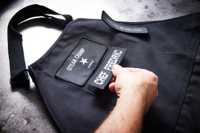 STEAK CHAMP Kochschürze 2 Taschen mit Klettverschluss für Beschriftung in Schwarz präsentiert im Onlineshop von KAQTU Design AG. Kochschürzen ist von STEAK CHAMP