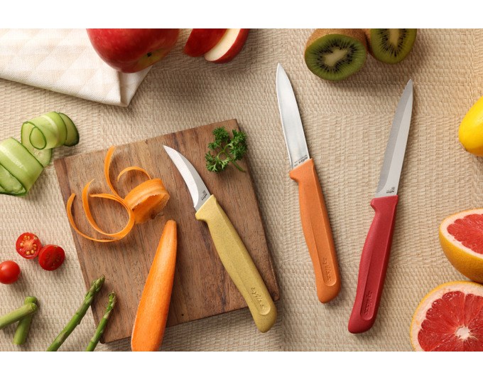 Drei ZYLISS Rüstmesser mit Edelstahlklingen in Orange, Rot und Gelb, ergonomische Griffe aus Weizenstrohmaterial, mit Klingenschutz.