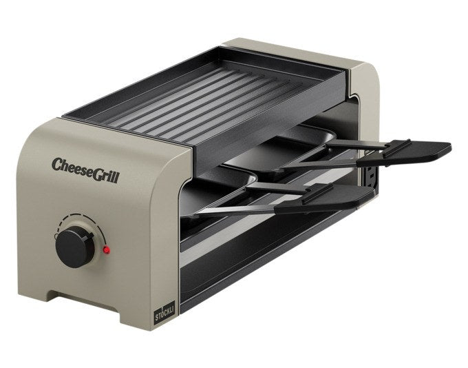 Tischgrill STÖCKLI CheeseGrill 2 Connect in Ivory Gold mit zwei Pfännchen, Wende-Grillplatte und Parkdeck auf hellem Hintergrund.