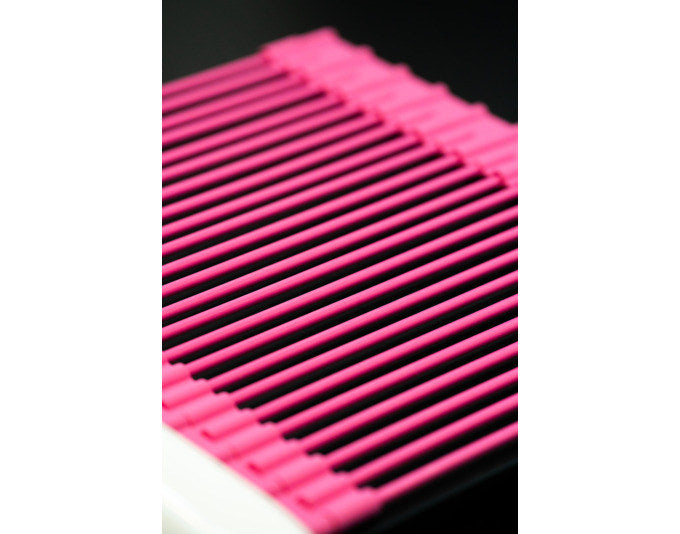 Pinkes Abtropfgitter aus Silikon mit Edelstahlkern, ausziehbar, auf einer Spüle liegend zum Abtropfen von Geschirr und Gemüse.