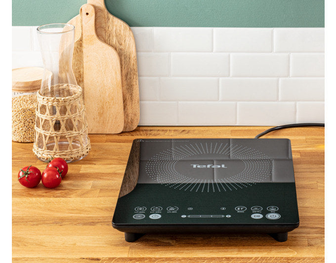 Schwarze TEFAL Induktionsplatte IH2108 mit digitalem Display und Bedienfeld, flache Bauform, auf heller Arbeitsfläche platziert.
