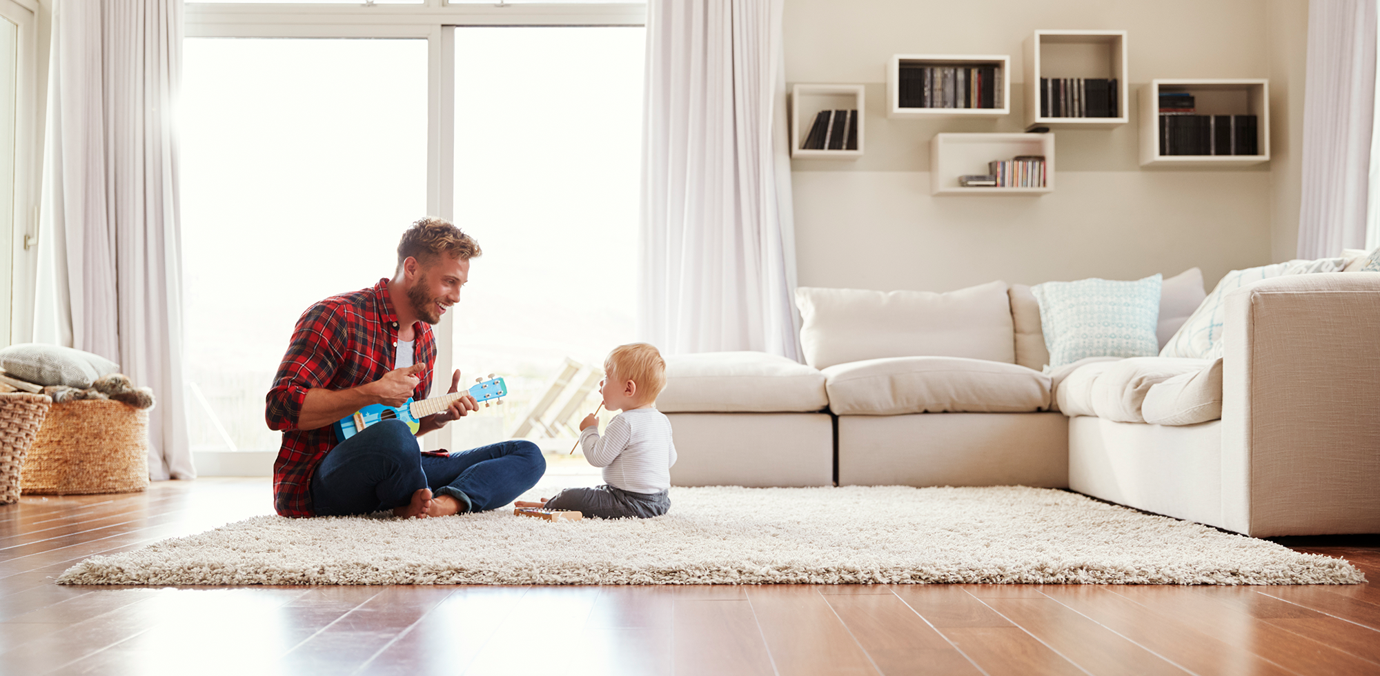 Vater spielt mit Sohn in schön eingerichtetem Wohnzimmer mit hellen Tönen