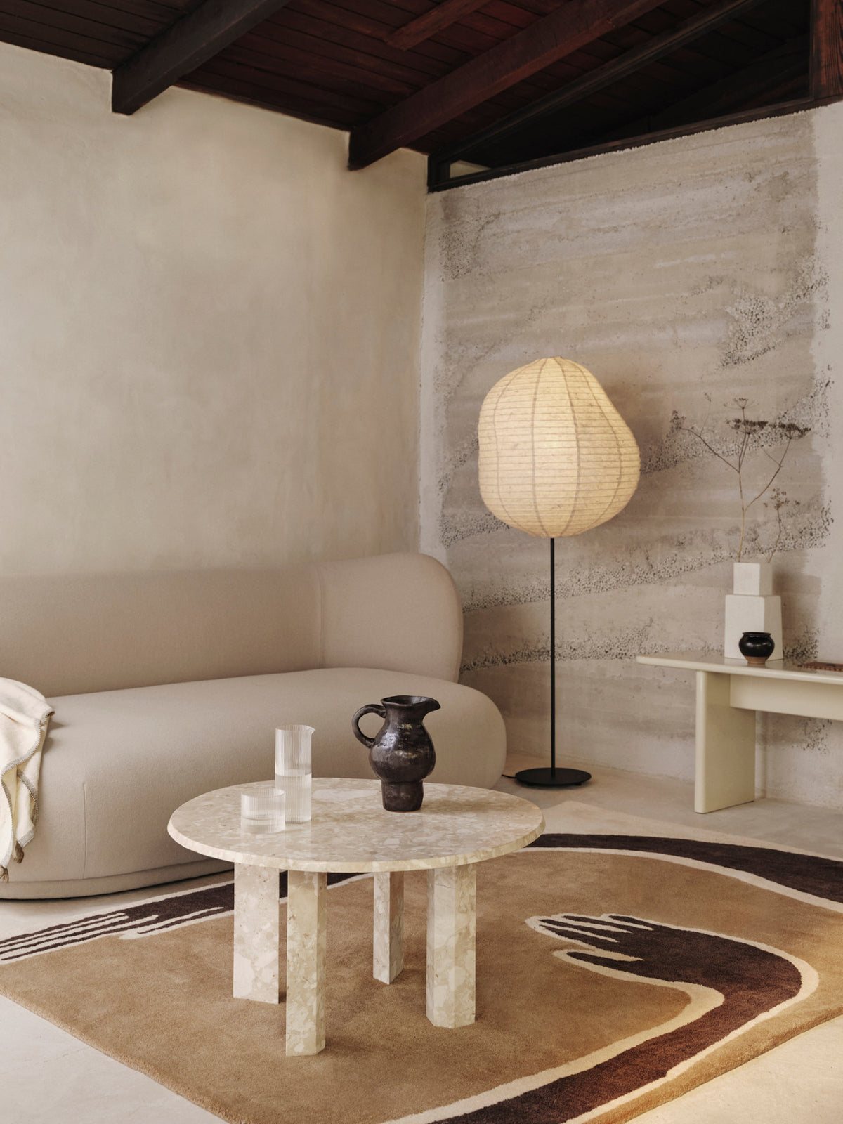 Getufteter Teppich Pose von Ferm Living in Dark Coffee/Offwhite mit stilisiertem Armmotiv, Vorderseite aus neuseeländischer Wolle, Rückseite aus Baumwolle.