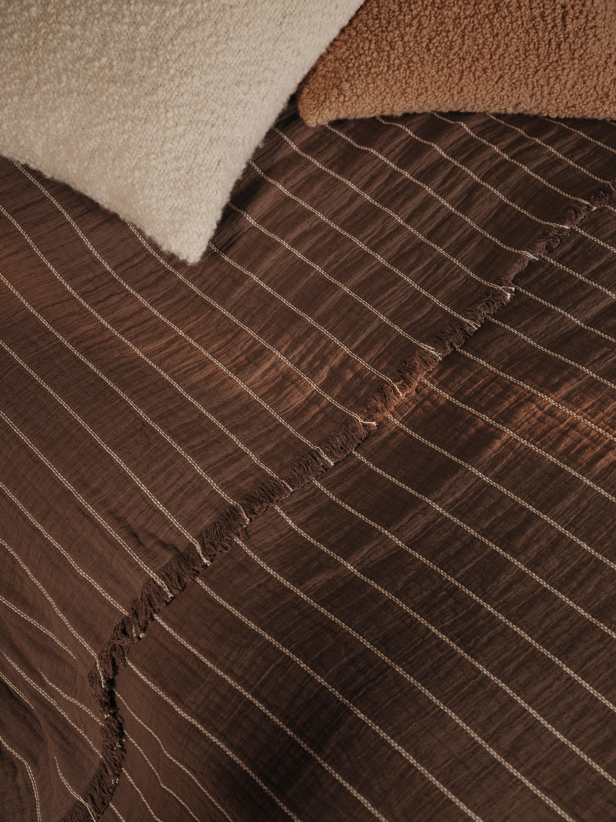 Aires Tagesdecke von Ferm Living in Stone, aus 100% Bio-Baumwolle, mit Doppelwebstruktur, kontrastierendem Streifen und Fransen an den Enden.