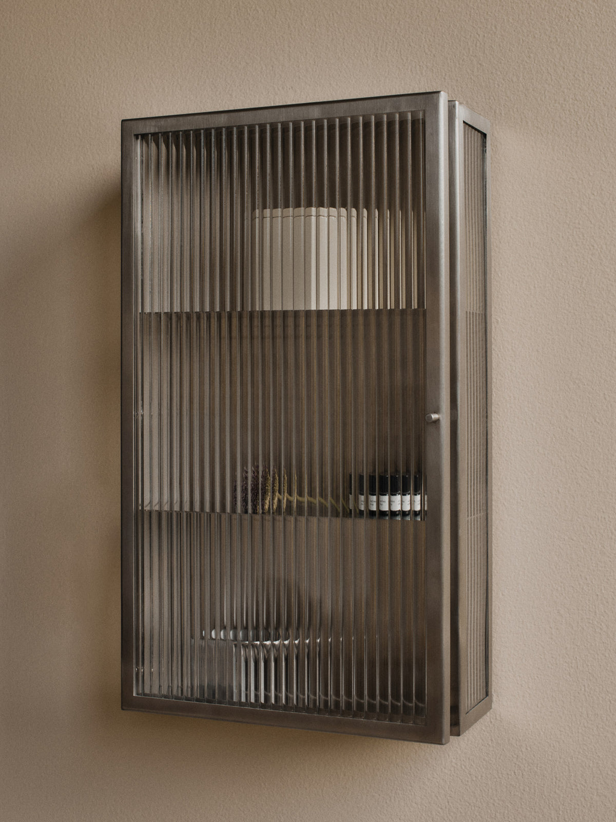 Haze Wandschrank von Ferm Living mit geriffelter Glastür und Gehäuse aus gebürstetem Edelstahl, schlanke, rechteckige Form, zwei Metallregale im Innern.