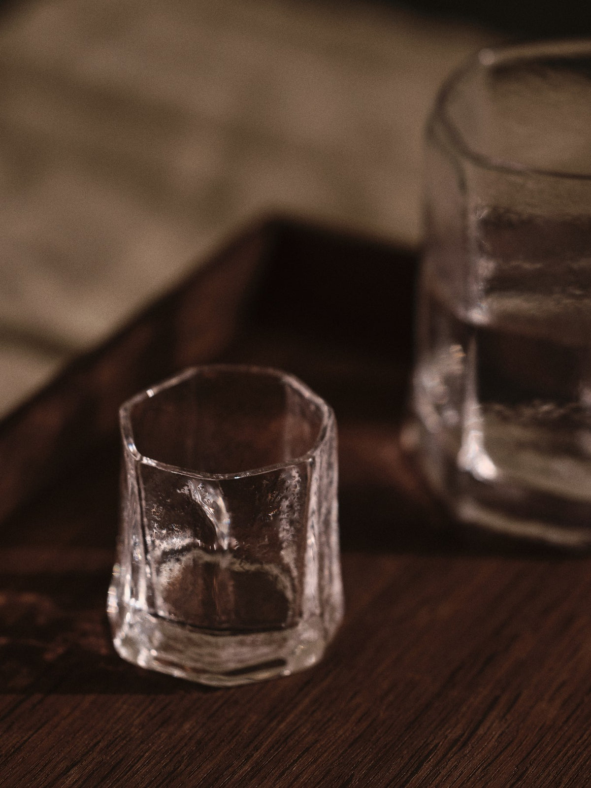 Zwei klare Kiru Gläser von Ferm Living aus mundgeblasenem recyceltem Glas mit skulpturaler, keramikähnlicher Oberflächenstruktur auf hellem Hintergrund.