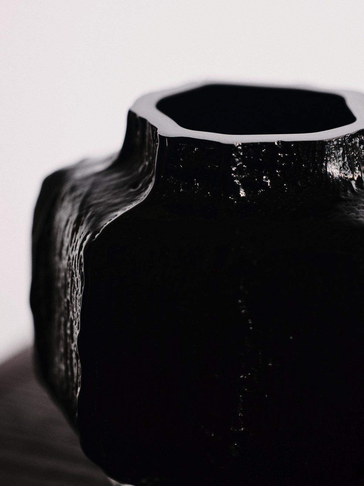 Schwarze Mokuri Vase aus mundgeblasenem, recyceltem Glas mit facettierter Oberfläche und vertikalen Linien, Höhe 15 cm.