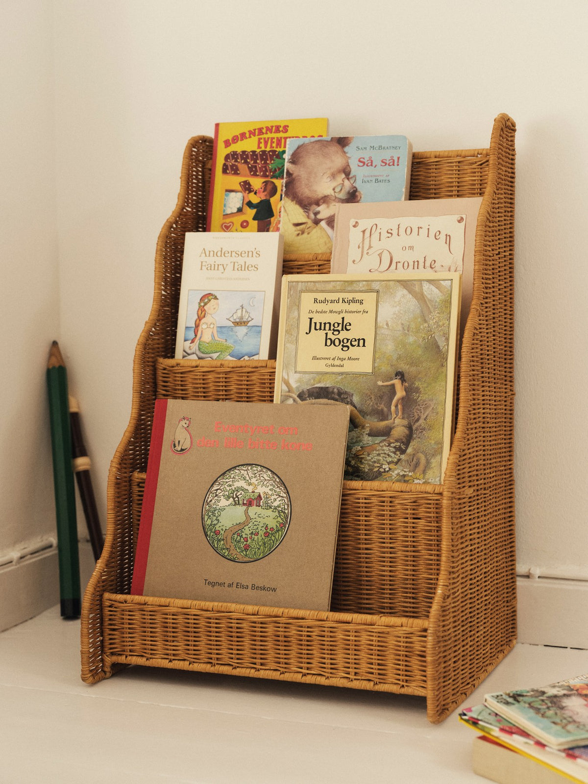 Foto eines Rivan Vitrinen-Bücherregals aus geflochtenem Rattan mit wellenförmigem Rand und nach vorne gerichteten Regalböden, Farbe Natur.