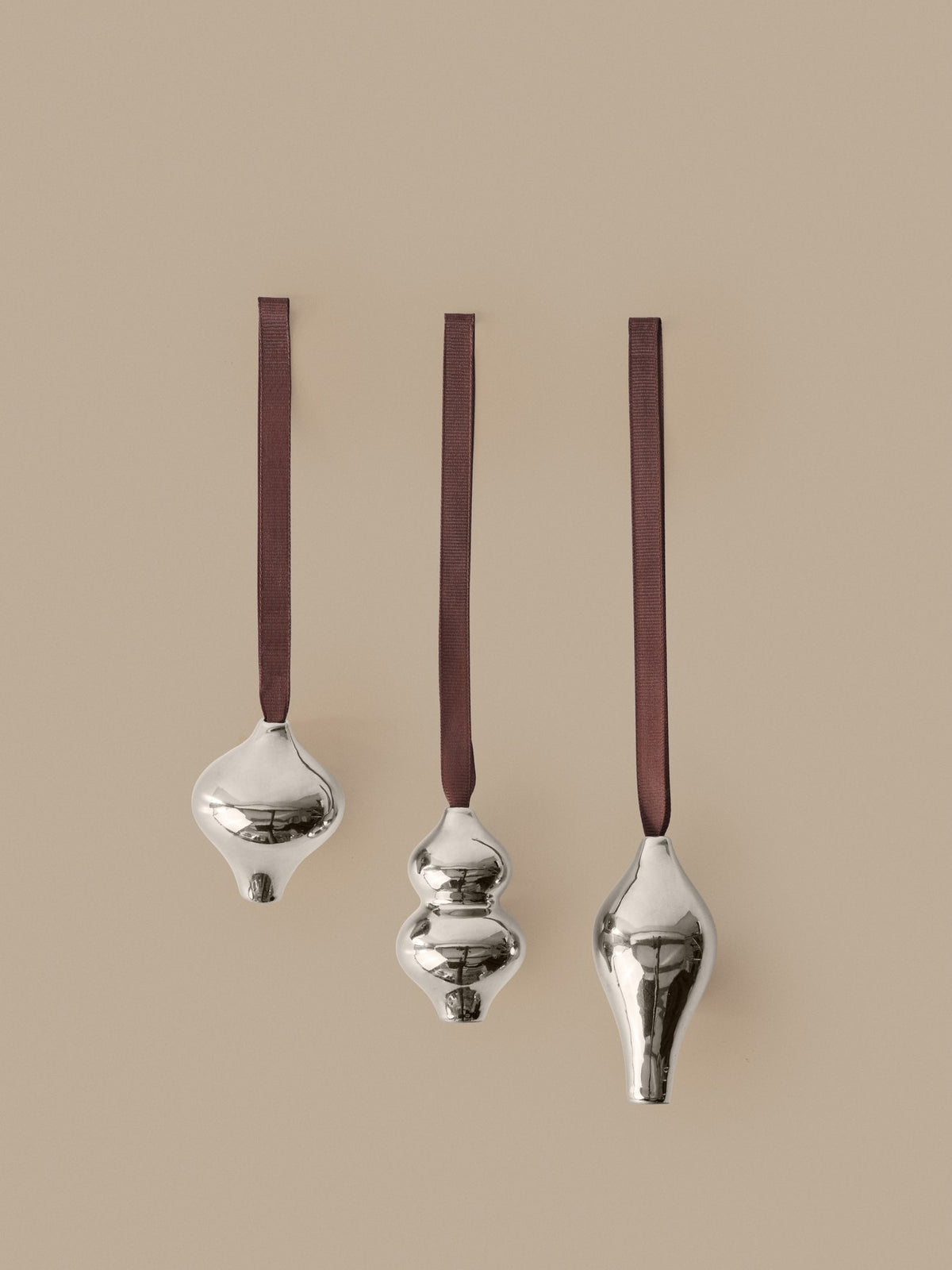 Drei silberfarbene Ornamente aus galvanisiertem Steingut mit Polyesterband, dekorativ angeordnet, Design von Ferm Living aus Dänemark.