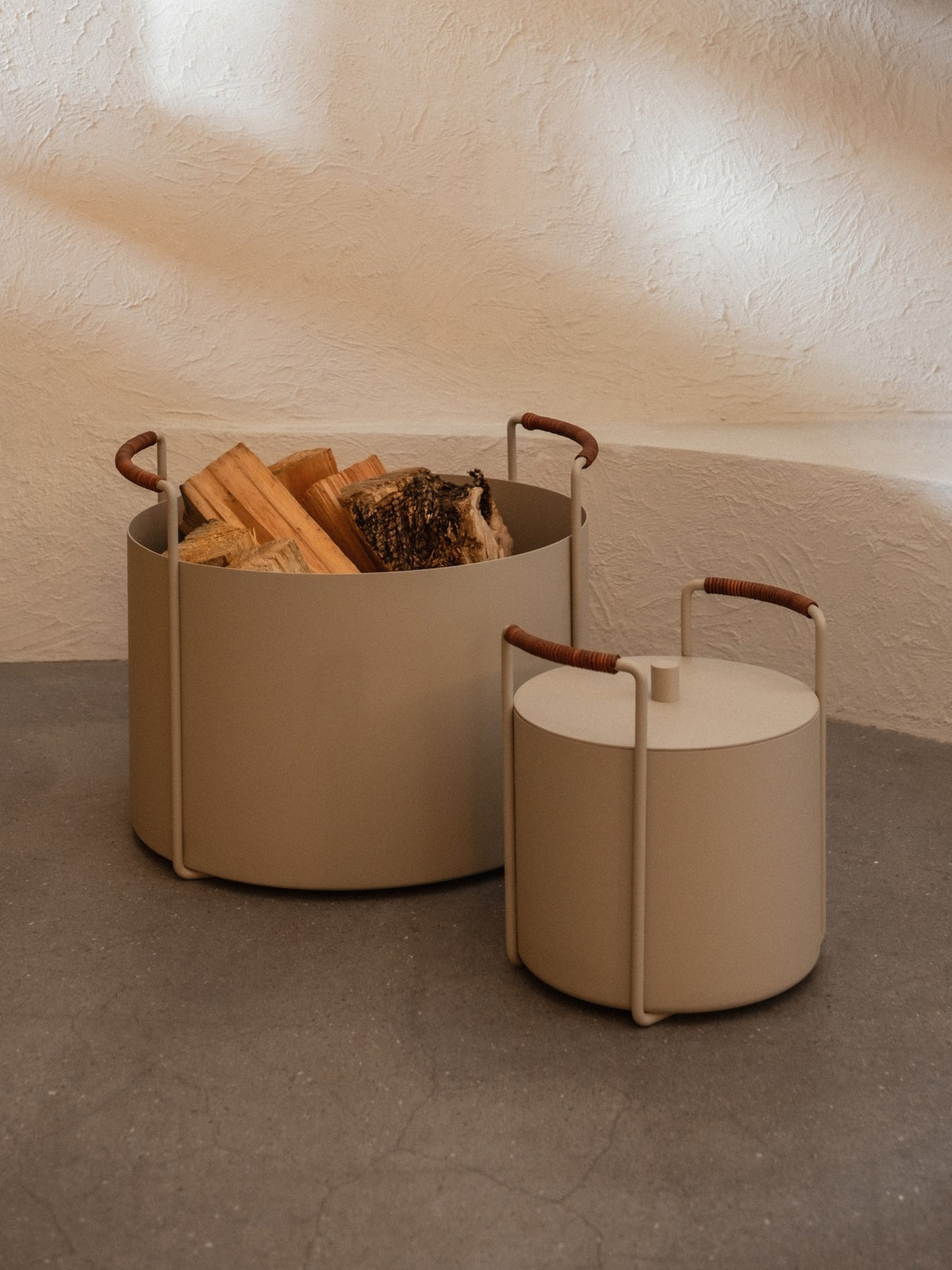 Cashmeefarbener Brennholzeimer aus pulverbeschichtetem Eisen mit ledernem Griff, minimalistische Form, für Kaminholz.