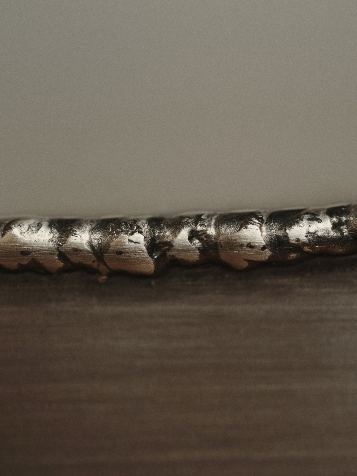 Ferra Couchtisch von Ferm Living aus gebürstetem Edelstahl mit sichtbaren, handverschweissten Kanten und leicht geschwungener Form.