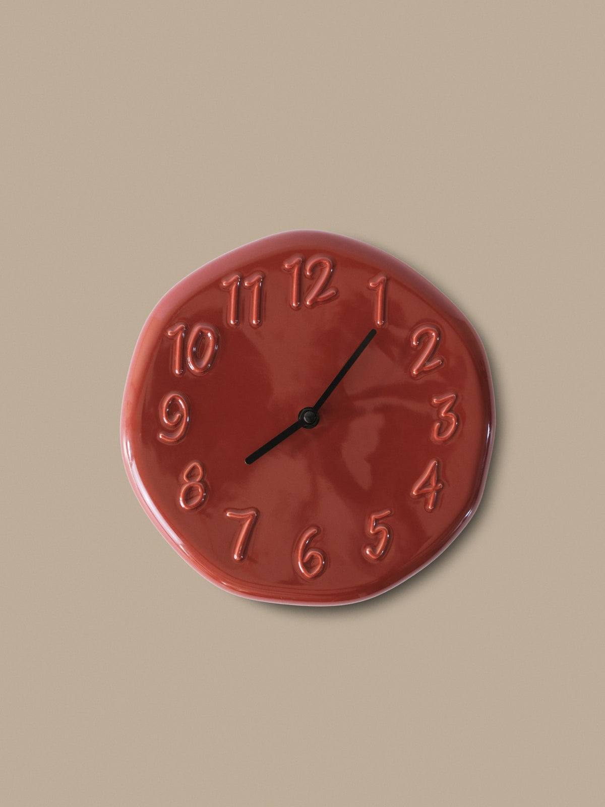 Runde Wanduhr aus glasiertem Steinzeug in Creme mit Aluminium-Zeigern und direkt in die Oberfläche modellierten Ziffern, leicht unregelmässige Form.
