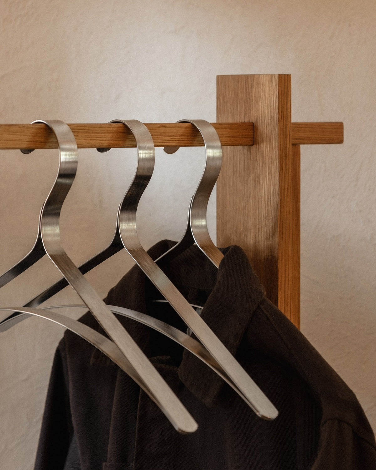 Drei Kleiderbügel aus Edelstahl mit schlanker, durchgehend gebogener Form, im Set von Ferm Living, glänzende Metalloberfläche sichtbar.
