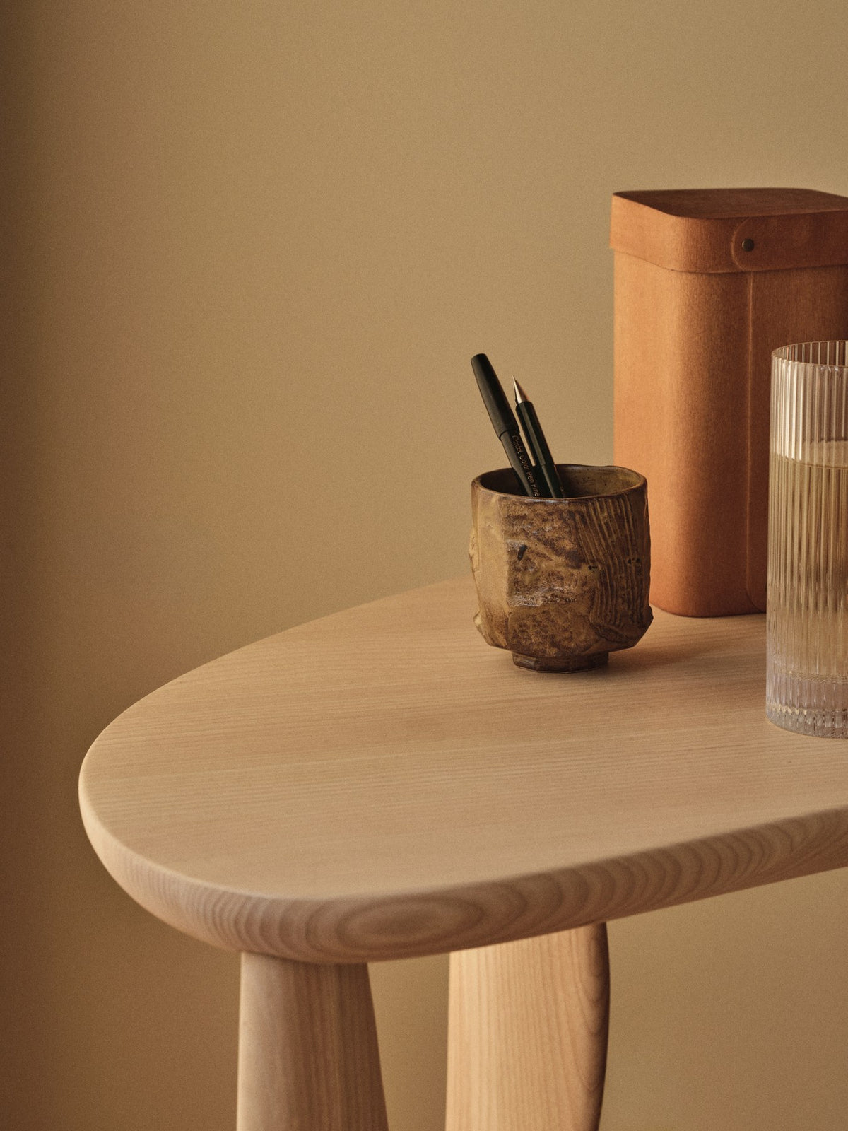 Feve Schreibtisch von Ferm Living aus massiver Esche in Natur, mit filigranen, elliptisch geschnitzten Beinen und verstellbaren Füssen.