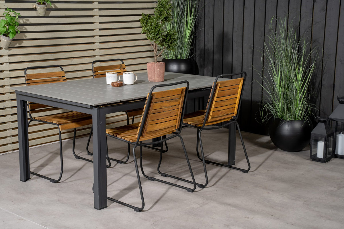 Rechteckiger Gartentisch mit grauer Aintwood-Tischplatte und schwarzem Stahlgestell, daneben zwei Esszimmerstühle aus Aintwood und Aluminium in Natur.