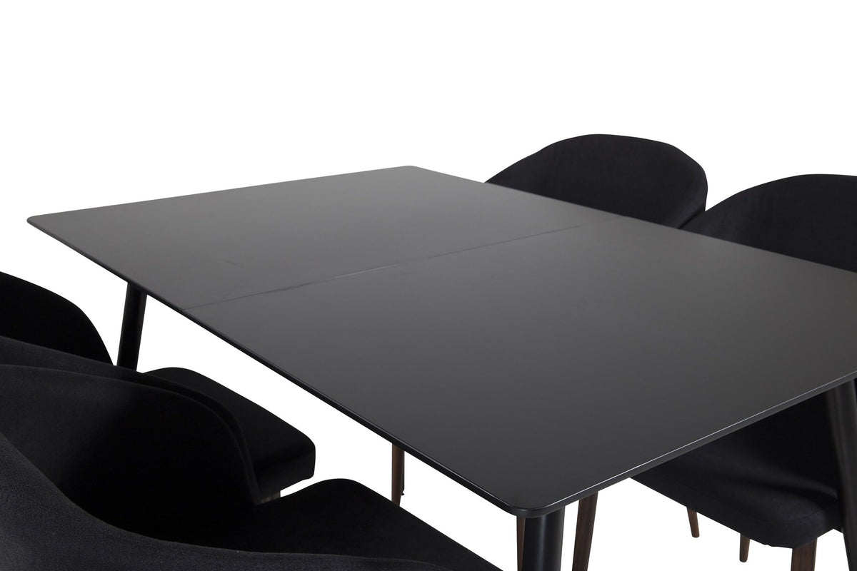 Rechteckiger Esstisch aus MDF und Stahl in Schwarz mit ausziehbarer Platte, daneben zwei Stühle mit Walnussbeinen und schwarzem Stoffbezug.