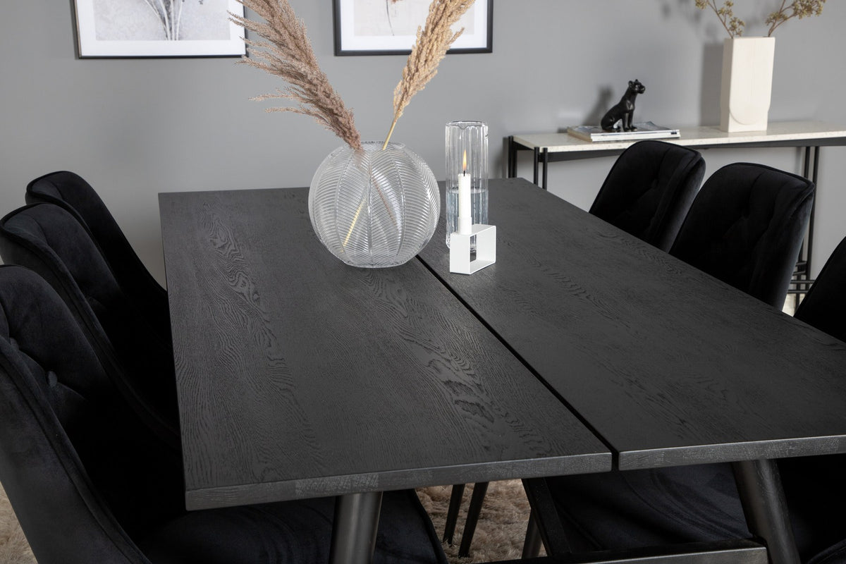 Rechteckiger Esstisch mit schwarzer Eichenplatte und Stahlbeinen, daneben zwei schwarze, gepolsterte Esszimmerstühle von Venture Home.