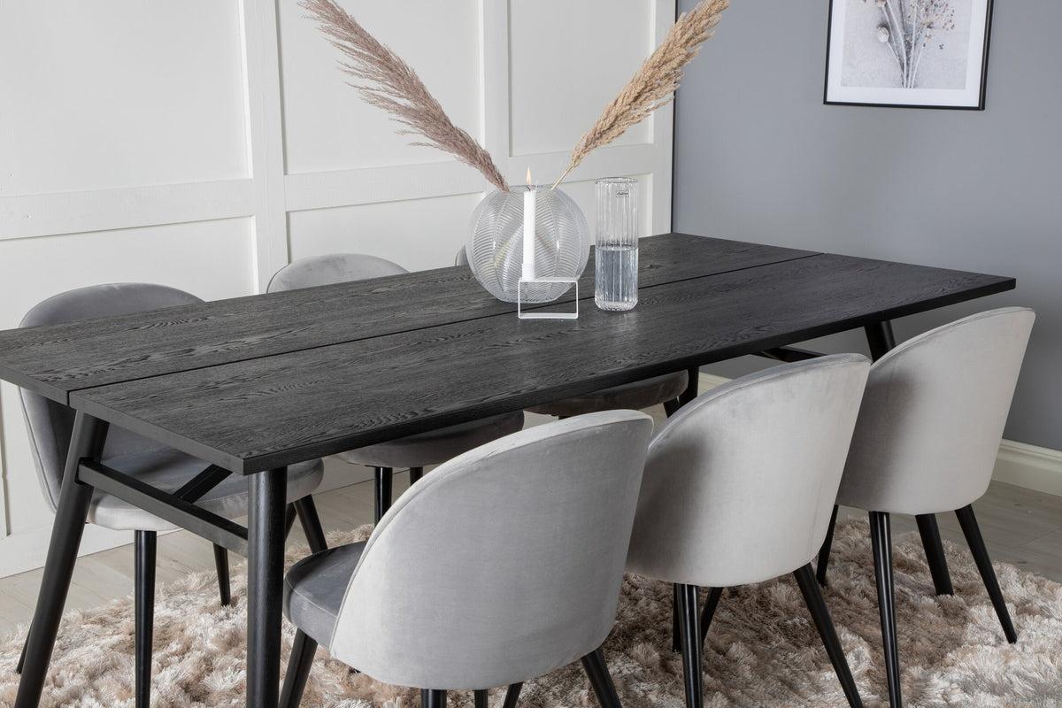 Rechteckiger Esstisch mit schwarzer Eichenplatte und Stahlbeinen, dazu zwei graue Stühle mit Stahlgestell aus dem Sleek & Velvet Set.