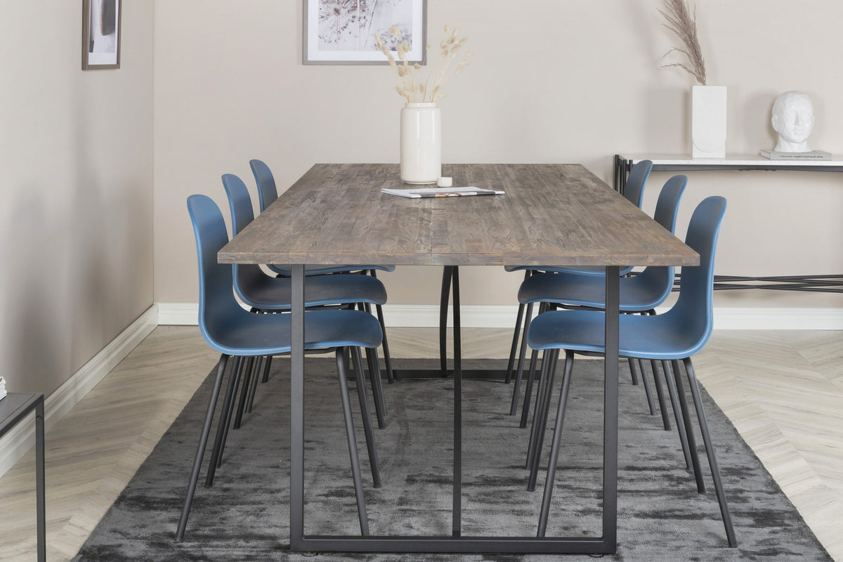 Esstisch Padang mit Teak-Tischplatte in Natur und Stahlbeinen, kombiniert mit blauen Arctic Stühlen mit schwarz pulverbeschichtetem Gestell.