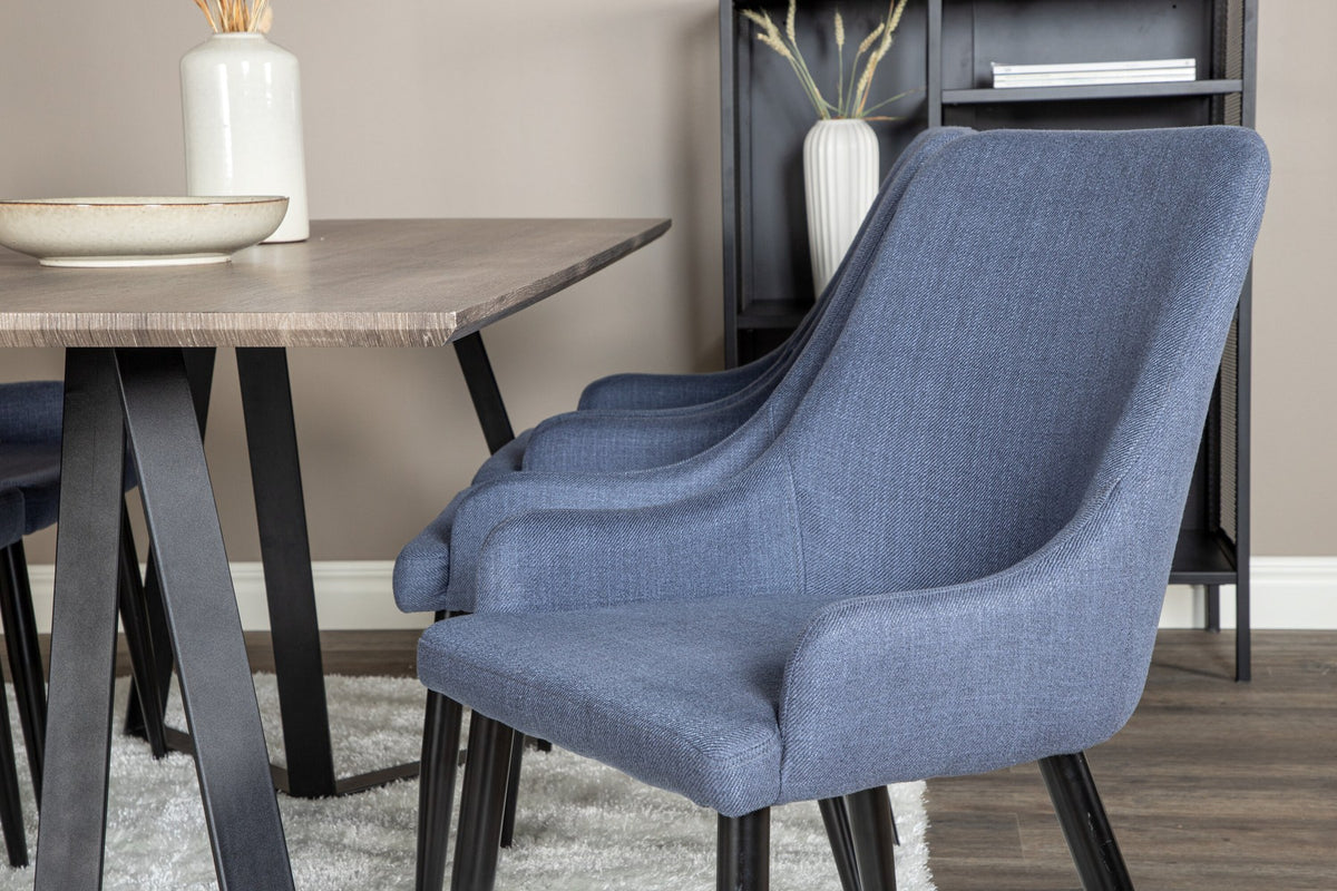 Zwei blaue Esszimmerstühle mit Stahlgestell und schwarz pulverbeschichteter Oberfläche neben einem rechteckigen MDF-Esstisch mit Stahlbeinen.
