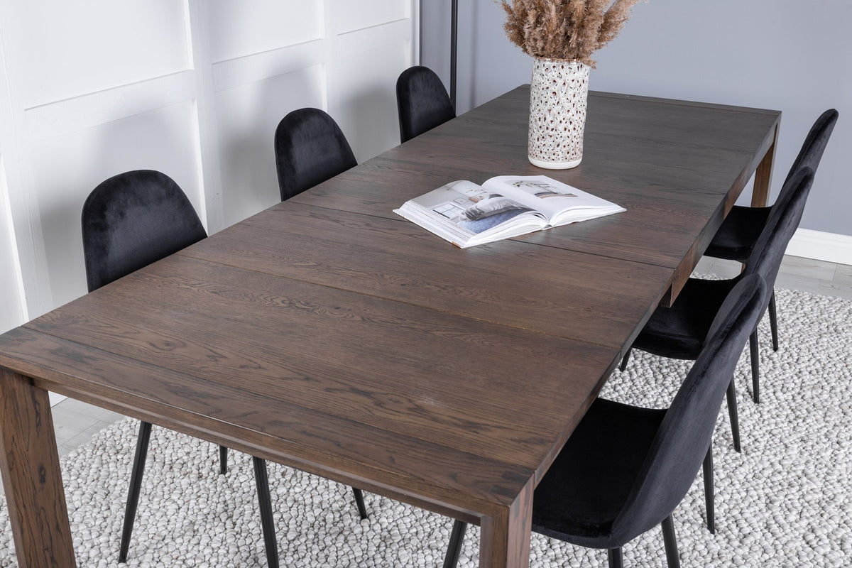 Rechteckiger Esstisch aus Eiche in Natur mit ausziehbarer Platte, dazu zwei schwarze Esszimmerstühle mit gepolsterter Sitzfläche von Venture Home.