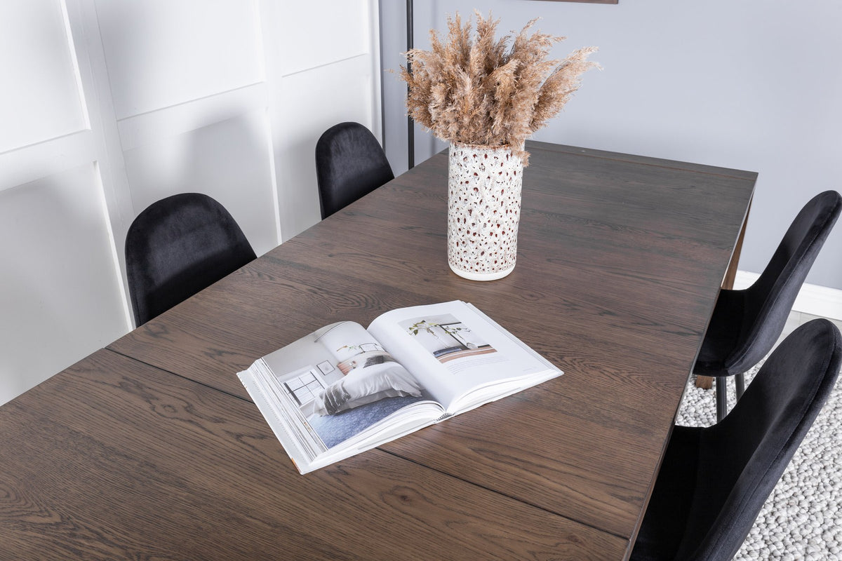 Rechteckiger Esstisch aus Eiche in Natur mit ausziehbarer Platte, dazu zwei schwarze Esszimmerstühle mit gepolsterter Sitzfläche von Venture Home.