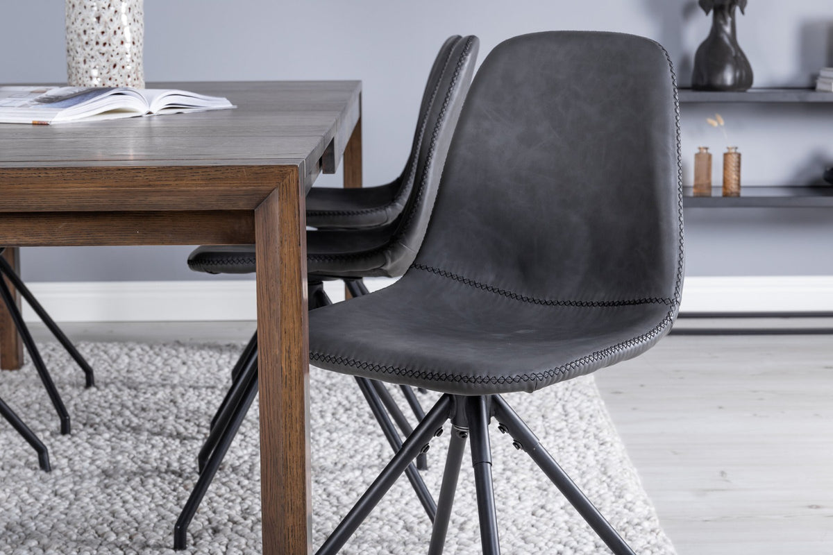 Rechteckiger Esstisch aus Eiche in Natur mit ausziehbarer Platte, dazu zwei schwarze Esszimmerstühle mit gepolsterter Sitzfläche von Venture Home.