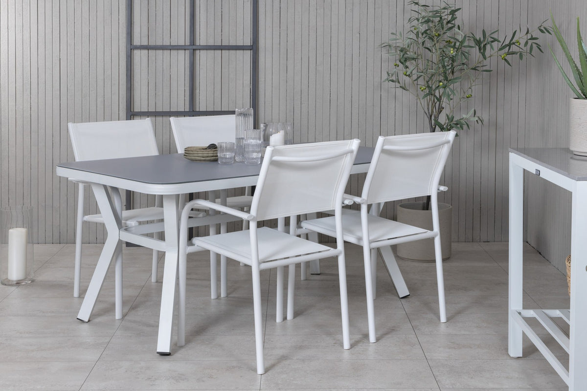 Rechteckiger Gartentisch mit schwarzer Mattglasplatte und Aluminiumbeinen, daneben zwei weisse Stühle aus Textilene mit Pulverbeschichtung.