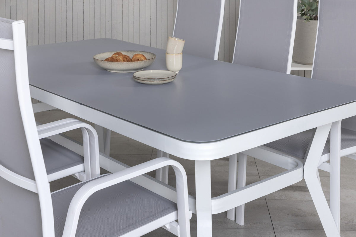 Rechteckiger Gartentisch mit Mattglas-Platte und Aluminiumbeinen, daneben zwei graue Relaxsessel aus Textilene von Venture Home.