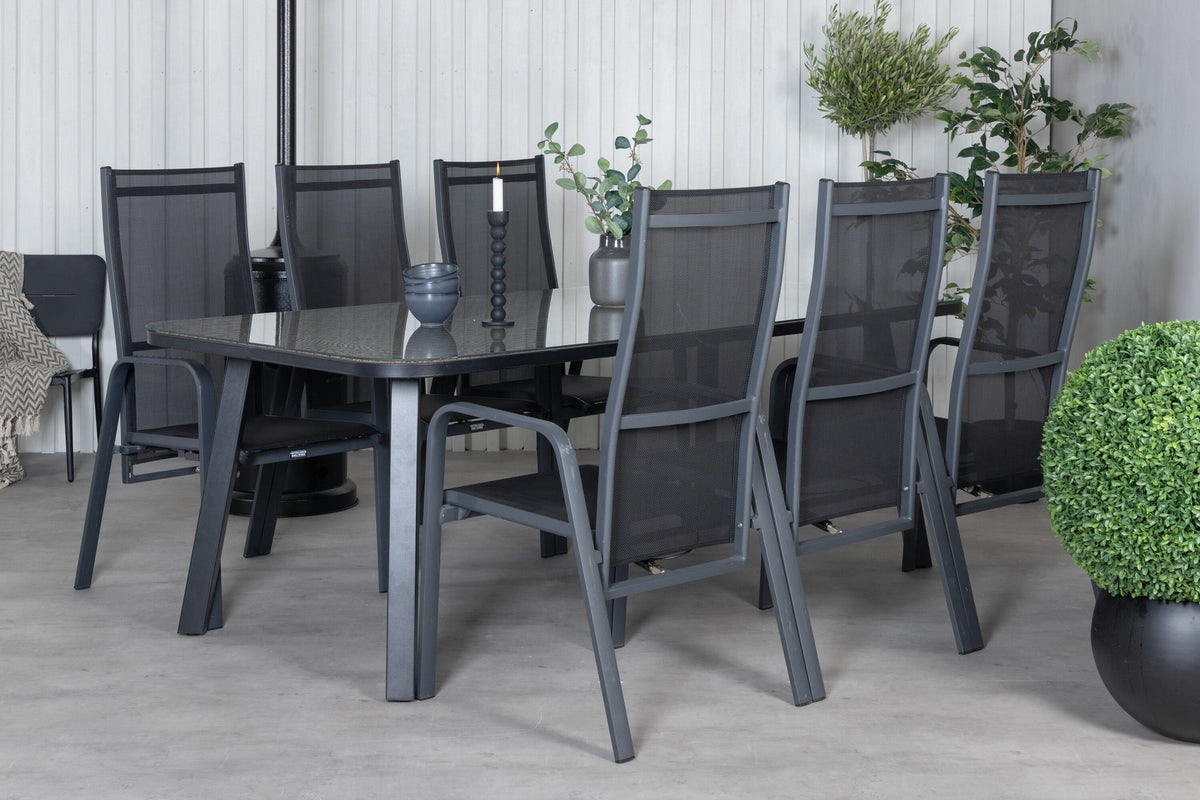 Schwarzer Gartentisch aus Glas und Aluminium mit zwei Relaxsesseln aus Polyesterseil, Stahl und Weide im Outdoor-Bereich.