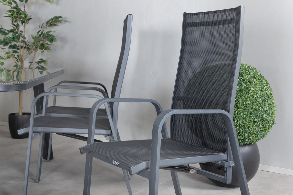 Schwarzer Gartentisch aus Glas und Aluminium mit zwei Relaxsesseln aus Polyesterseil, Stahl und Weide im Outdoor-Bereich.