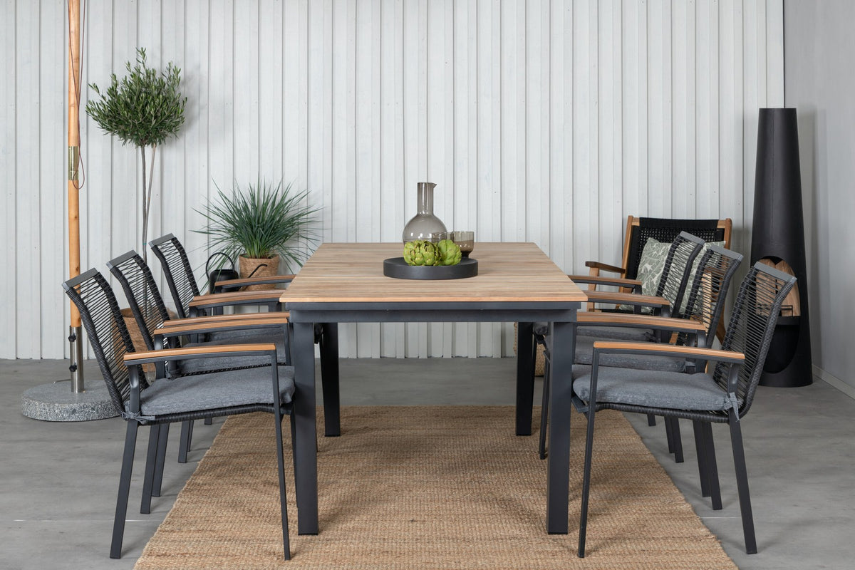 Foto eines schwarzen 2er-Stuhlsets mit Aluminiumgestell und Polyesterbezug neben einem rechteckigen Teak-Esstisch in Natur mit Stahlbeinen.
