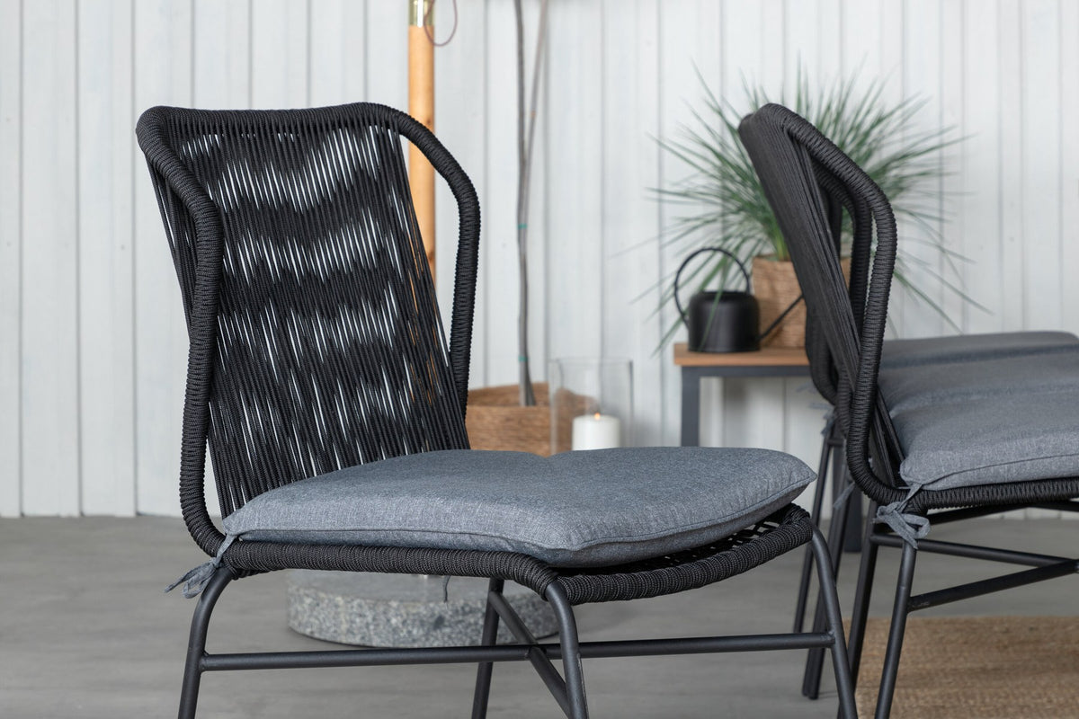 Vier schwarze Esszimmerstühle aus Aluminium mit Seilbezug und ausziehbarer rechteckiger Teakholz-Esstisch mit Stahlbeinen, Naturfarben.