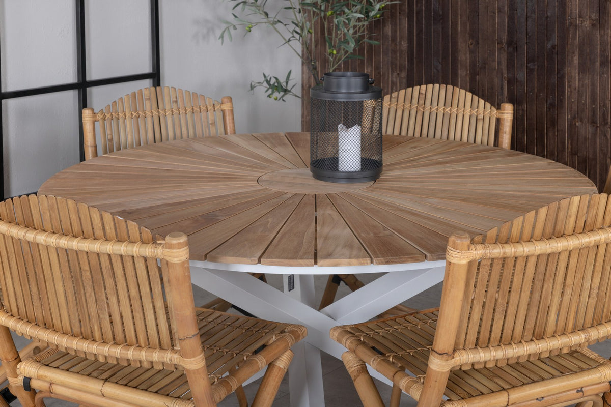 Runder Esstisch ⌀140 aus Teakholz mit Rattanbeinen neben Caféstuhl mit Aluminiumgestell und Bezug aus Baumwolle und Polyester in Naturfarbe.