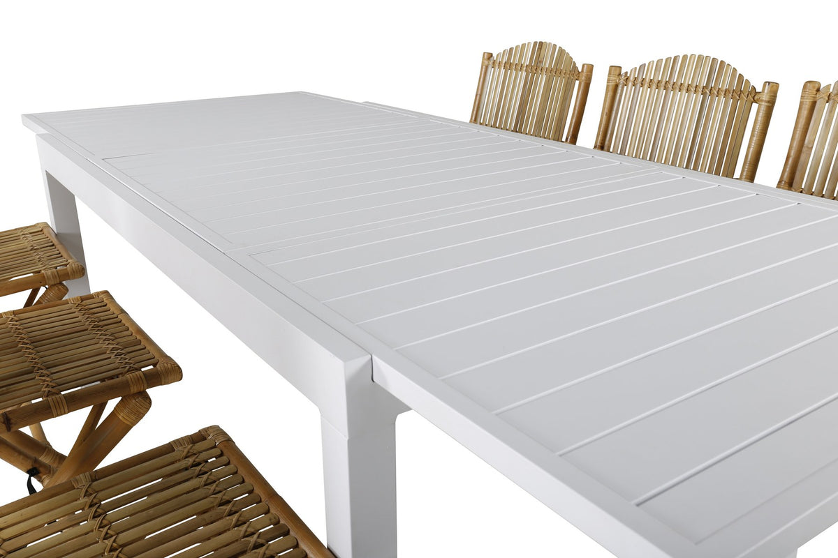 Aluminium-Caféstuhl in Natur mit Baumwoll-Polyester-Bezug neben rechteckigem Esstisch mit weisser Aluminium-Tischplatte und Rattanbeinen.