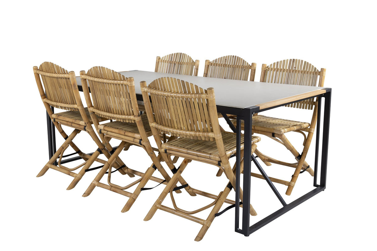 Rechteckiger Esstisch mit Glasplatte und Teakholzkante, schwarzem Metallgestell sowie Cane-Stühlen aus Rattan mit Bezug in Naturtönen.