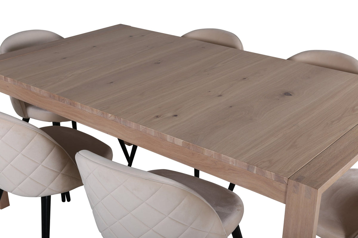 Rechteckiger Esstisch mit Eichenplatte in Whitewash und zwei gepolsterten Stühlen mit beigem Samtbezug und schwarzen Metallbeinen im Esszimmer.
