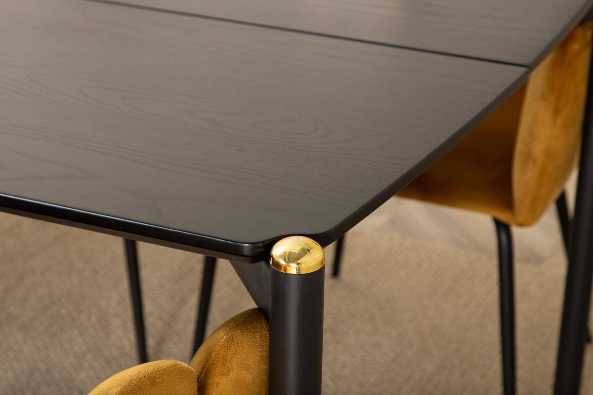 Schwarzer Esstisch aus MDF mit Furnier und Metallbeinen, kombiniert mit sechs Stühlen mit gelbem Samtbezug und schwarzen Metallbeinen.