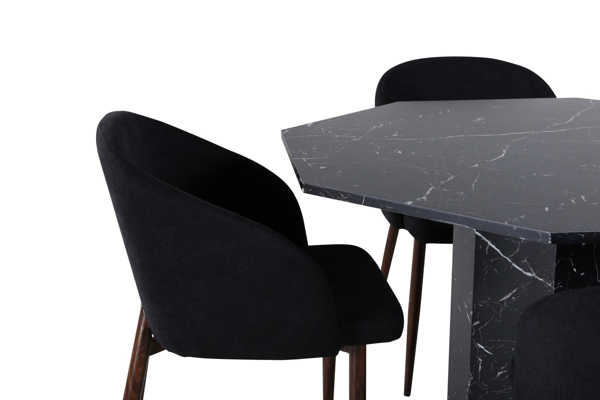 Zwei schwarze Esszimmerstühle mit Nussbaum-Beinen und Polyester-Sitzfläche neben rundem Esstisch Ø110cm mit schwarzer MDF-Platte und Stahlbeinen.