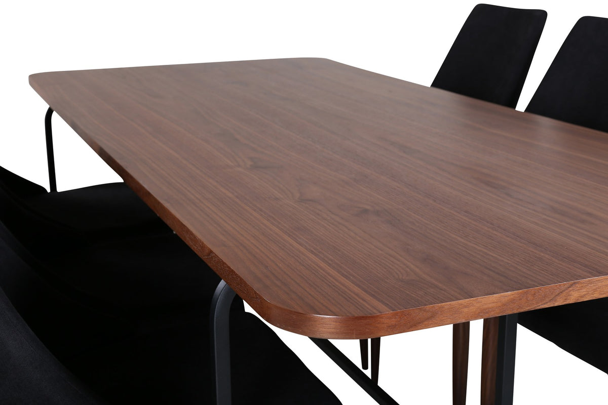 Rechteckiger Esstisch mit MDF-Tischplatte in Nussbaumfurnier und schwarzem Stahlgestell, kombiniert mit zwei schwarzen Polyester-Stühlen.