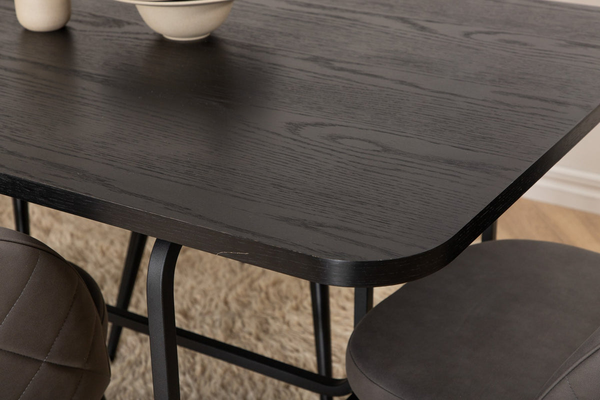 Esszimmerset Uno & Velvet: rechteckiger Esstisch mit schwarzer MDF-Furnier-Platte und Metallgestell, dazu Stühle mit grauem Samtbezug und Eisenbeinen.