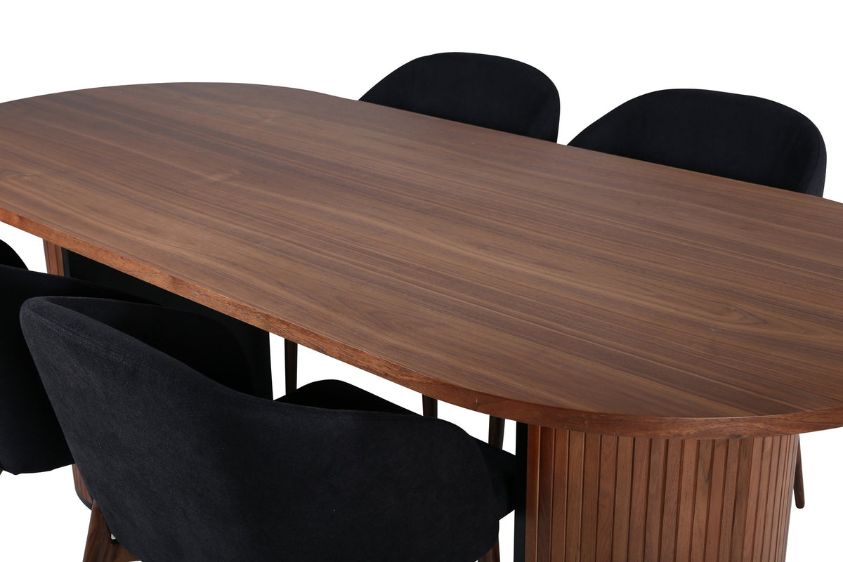 Ovaler Esstisch mit Nussbaum-MDF-Furnierplatte und Stahlgestell, daneben zwei schwarze Polsterstühle mit Metallbeinen im Esszimmer.