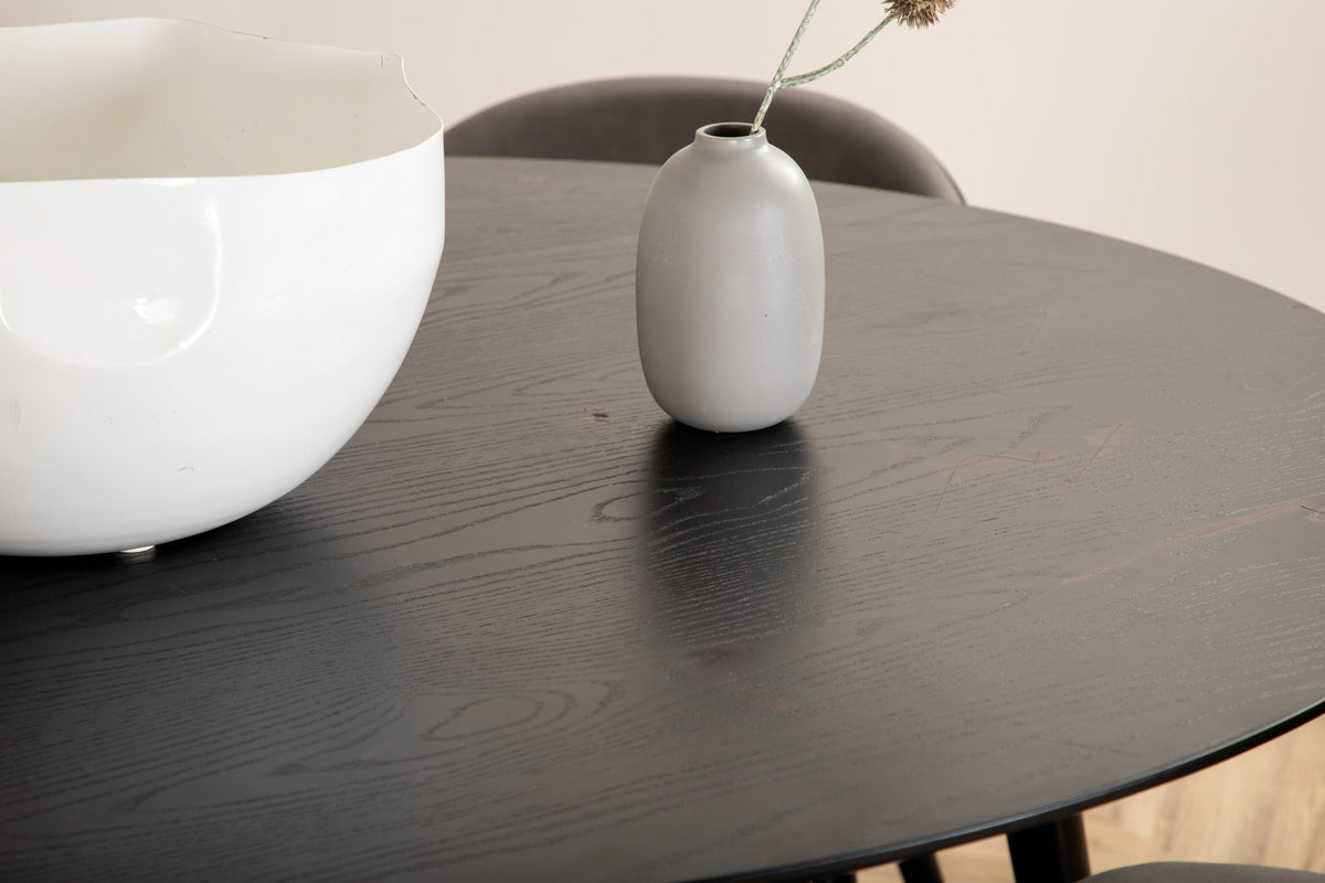 Rundes Dipp Esszimmerset: Esstisch ⌀115 cm mit schwarzem Furnier und schwarzen Beinen, dazu vier Velvet-Stühle mit schwarz-grauem Mikrofaserbezug.