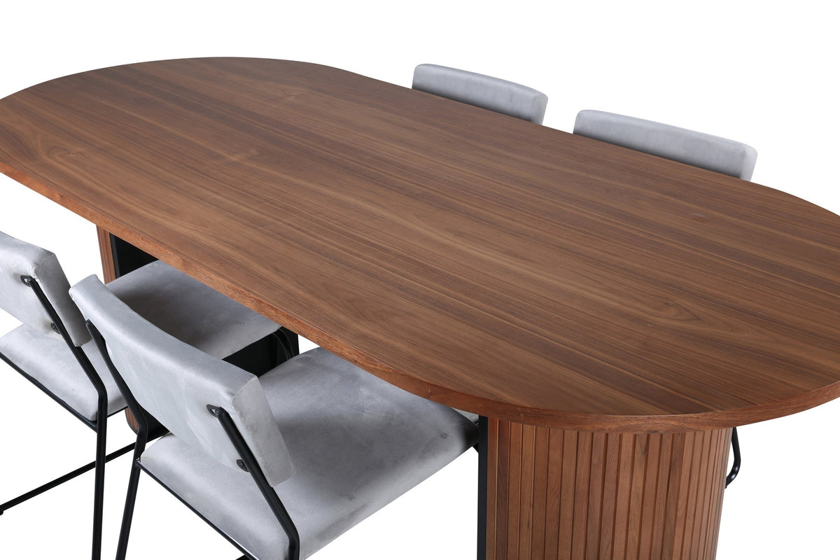 Zwei graue Esszimmerstühle mit schmalen Metallbeinen und samtigem Sitz neben ovalem Esstisch aus Nussbaum-MDF mit Furnier, 200x90cm.