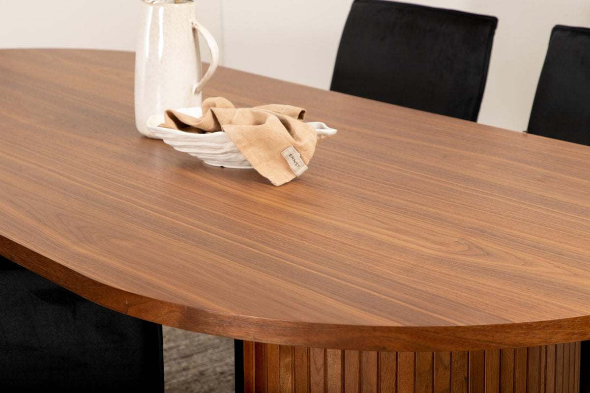Ovaler Esstisch aus MDF mit Nussbaum-Furnier, 200x90 cm, kombiniert mit vier schwarzen Esszimmerstühlen mit pulverbeschichteter Oberfläche.