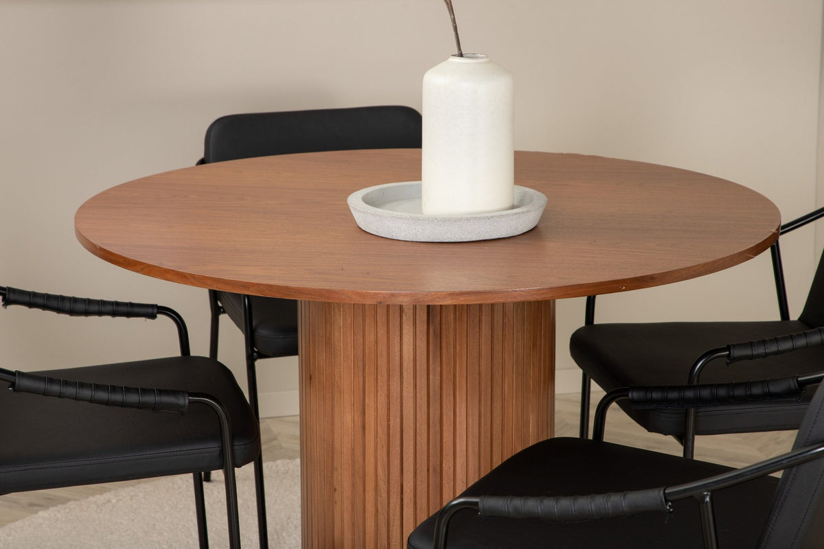 Rundes Esszimmerset mit Tisch aus MDF in Nussbaum-Optik ⌀110 cm und zwei schwarzen Stühlen mit Pulverbeschichtung und Eisenbeinen.