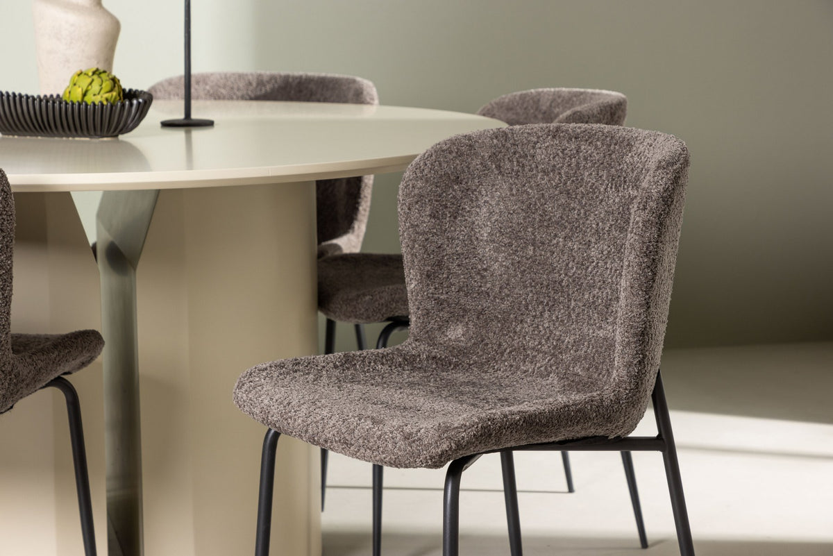 Rundes Esszimmerset aus MDF mit beiger Tischplatte Ø140 cm und zwei braunen Stühlen mit Bouclé-Bezug und schwarzem Metallgestell.