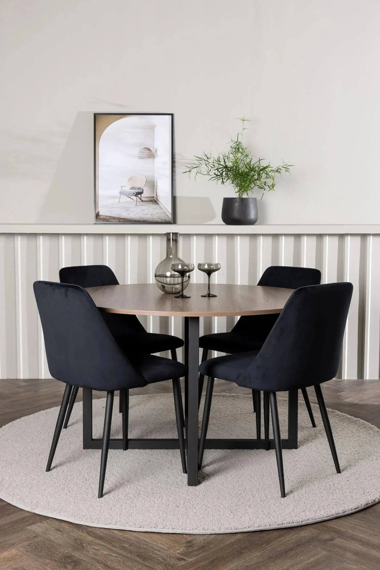 Stilvolles Durango Esszimmerset: Runder Tisch in Walnussoptik, schwarze Stahlbeine, samtbezogene Stühle. Skandinavisches Design für gesellige Runden.
